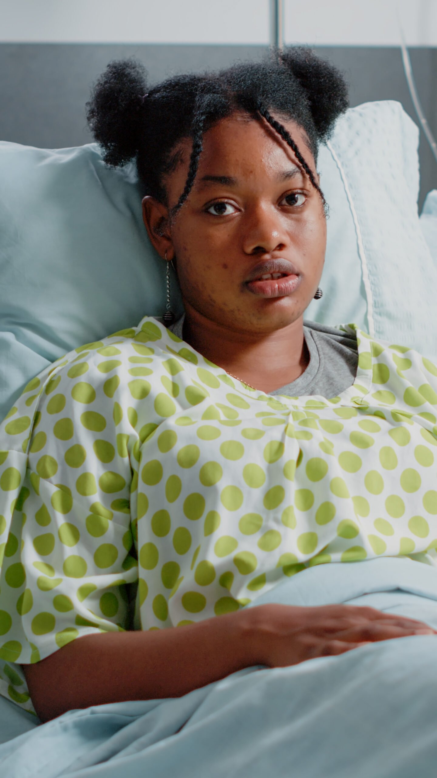portrait of woman with iv drip bag in hospital ward bed